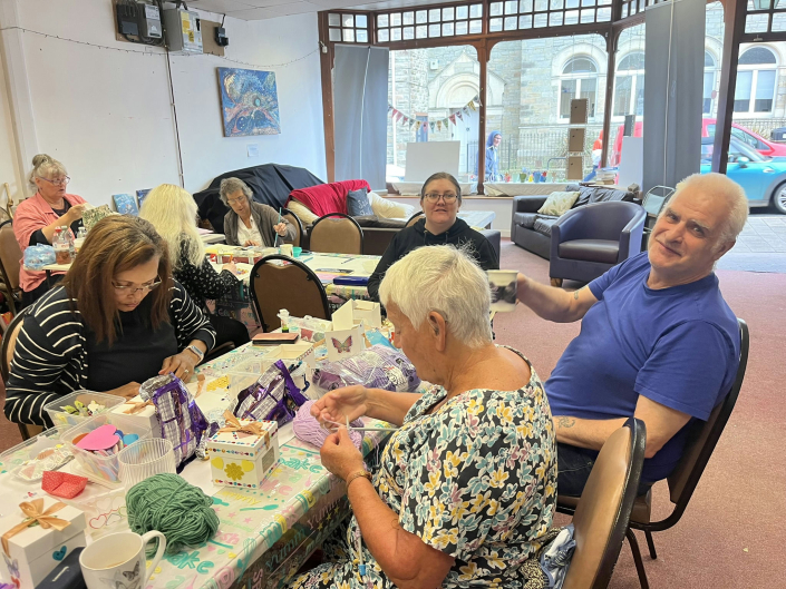 A group of people sitting around a table doing craft activities.